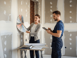 Contractor and client reviewing a wall color palette in an unfinished room, with the contractor using a tablet to document or confirm the selection — representing real-time selection tracking and approval.