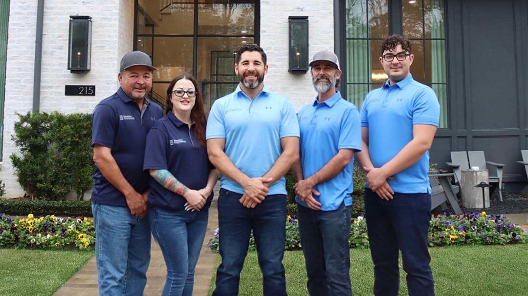 Group of five construction professionals in blue shirts standing outside a building, featured image