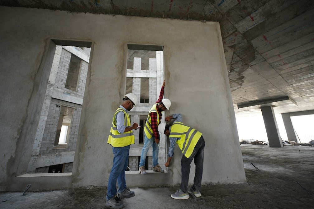 Construction crew using a mobile phone to complete a daily field report checklist on-site inside a concrete structure, showing real-time task tracking with TaskTag.